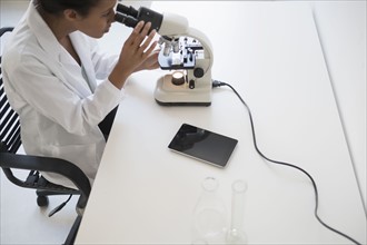 Woman scientist looking through microscope.