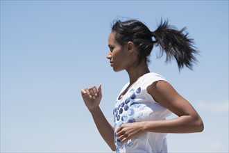 Profile of woman jogging against sky.