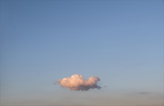 Single cloud on blue sky at sunset.