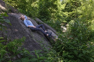 Woman lying on stone in forest.