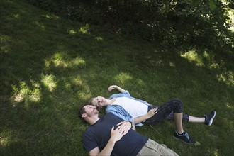 Couple lying on grass in forest.