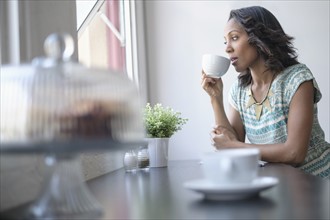 Woman drinking coffee by window.