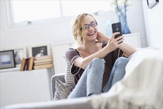 Woman sitting on sofa and using mobile phone.