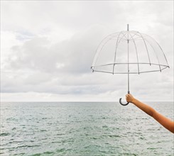 Person holding umbrella against cloudy sky