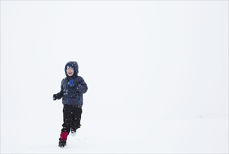 Boy (6-7) running in snow