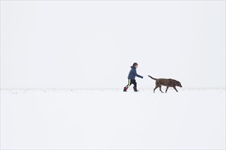Boy (6-7) walking with dog in winter