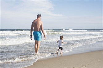 Father with daughter (18-23 months) walking on beach