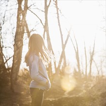 Side view of girl (10-11) standing in sunny forest