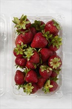 Overhead view of fresh strawberries in plastic container