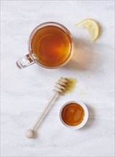 Overhead view of cup of tea and bowl of honey on marble table