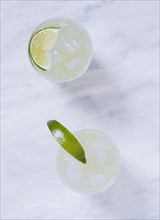 Overhead view of two margaritas on marble table