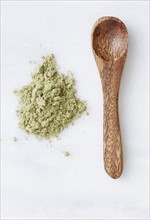 Overhead view of wooden spoon and green powder