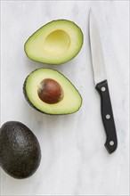 Overhead view of halved avocado and knife