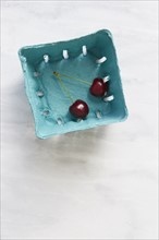 Overhead view of cherries in blue fruit carton