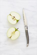 Overhead view of halved apple and knife