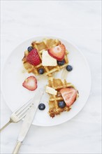 Overhead view of waffles with strawberries and blueberries