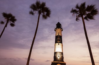 Peru, Lima, Miraflores, Faro De La Marina and palm trees at sunset