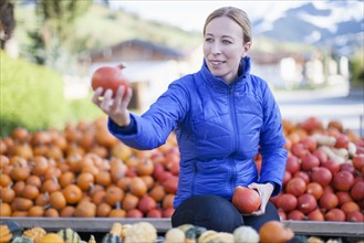 Austria, Salzburger Land, Maria Alm, Mature woman in blue jacket holding red vegetables