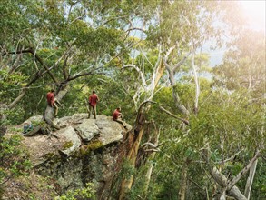 Australia, New South Wales, Katoomba, Three people on cliff in forest in Blue Mountains