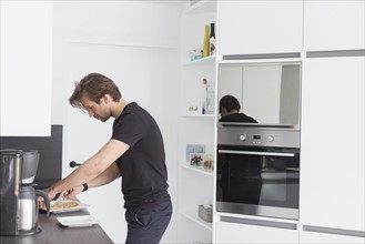 Mid-adult man preparing breakfast in modern kitchen