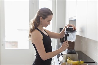 Mid-adult woman preparing smoothie