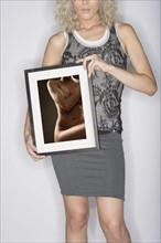 Studio shot of young woman holding photograph.