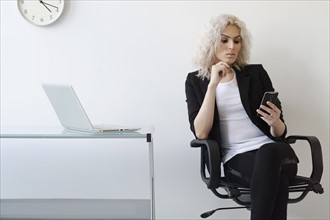 Young businesswoman using phone in office.