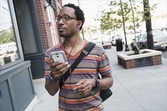 Mid adult man with phone in street.
