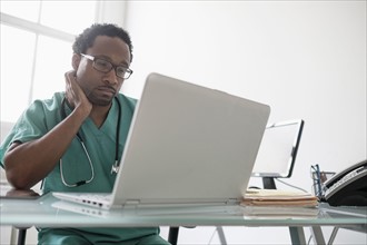Male doctor working with laptop at desk.