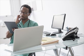 Male doctor working with digital tablet at desk.