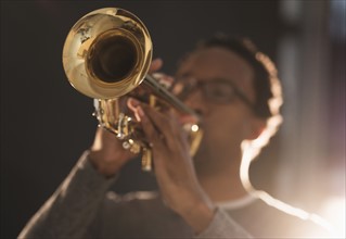 Mid adult man playing trumpet.