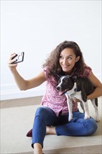 Woman holding dog, taking selfie.