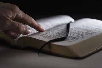 Human finger on open Bible.