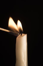 Studio shot of burning match igniting candle.