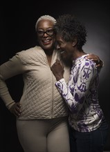 Two women laughing and standing in embrace.