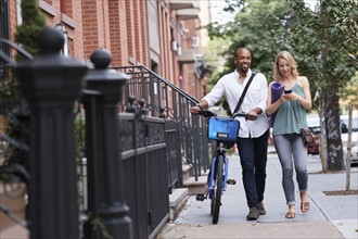 Couple walking with bicycle and exercising mat.
