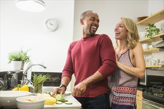 Couple preparing dinner in kitchen and laughing.