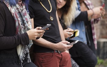 Young people standing in row using smartphones.