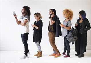 Young people standing in line using smartphones.