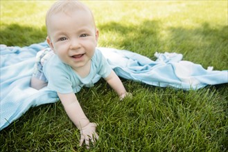 Baby boy (6-11 months) crawling on grass