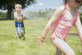 USA, Pennsylvania, Washington Crossing, Boy (4-5) and girl (2-3) playing with water hose