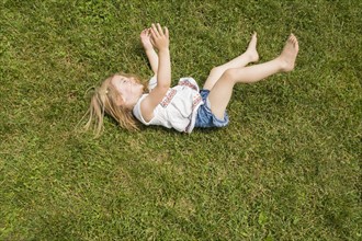 Girl (2-3) rolling on grass