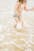 Girl (2-3) wading in ocean and splashing