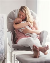 Mother sitting in armchair and kissing baby son (0-1 months)