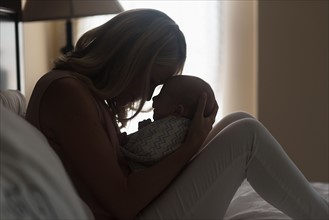 Mother holding son (0-1 months) in bedroom