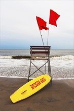 USA, New York State, New York City, Brooklyn, Yellow surfboard and empty lifeguard stand on beach