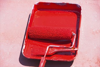 Paint roller in tray with red paint
