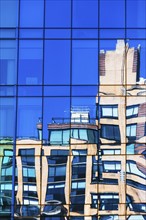 USA, New York, New York City, Building reflected in glass facade of office building