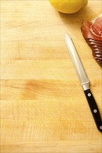 Spoon, lemon and slices of meat on cutting board