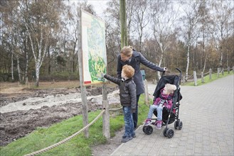 Mother and children (4-5, 8-9) looking at map in park